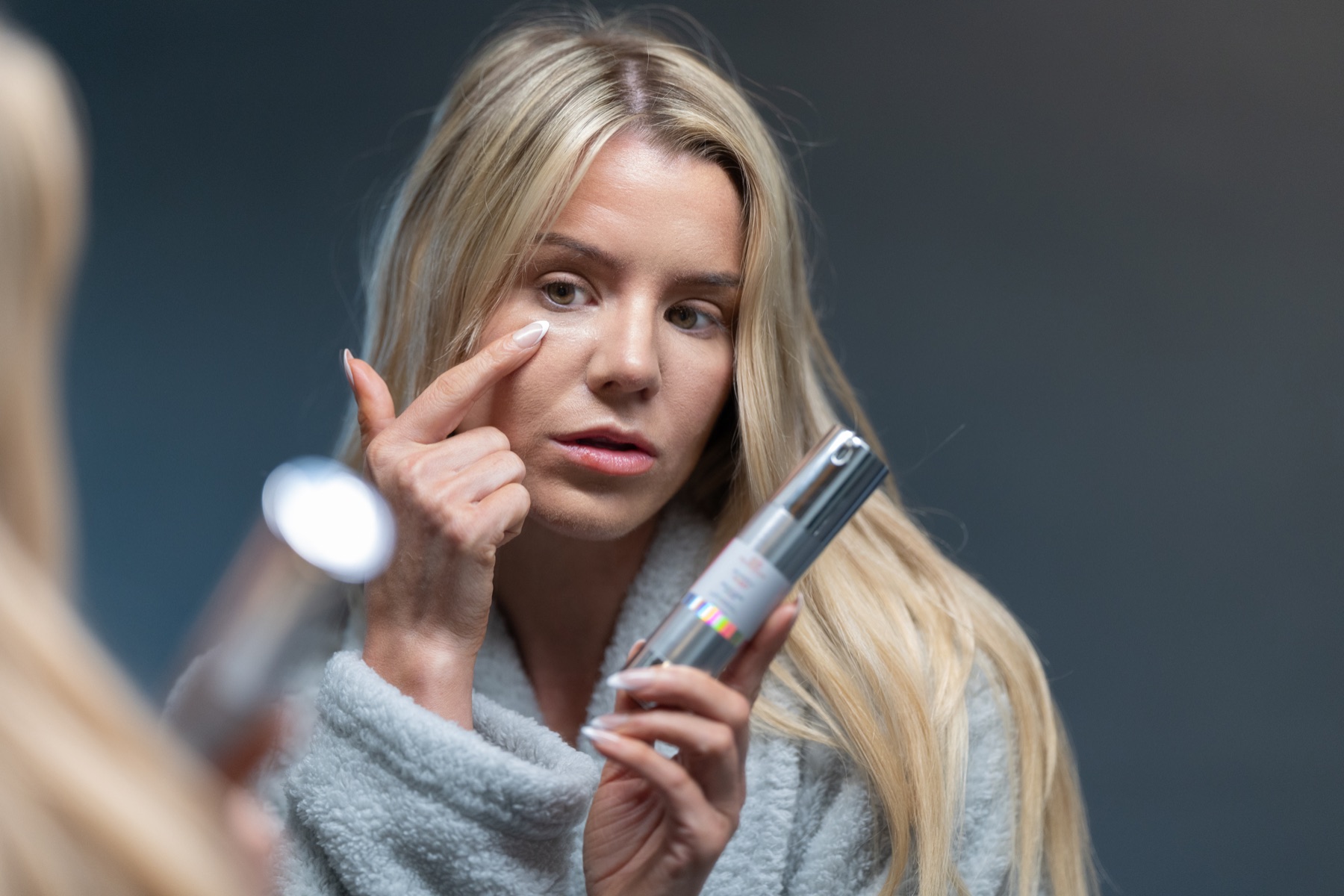 Model applying brightening serum beneath the eye