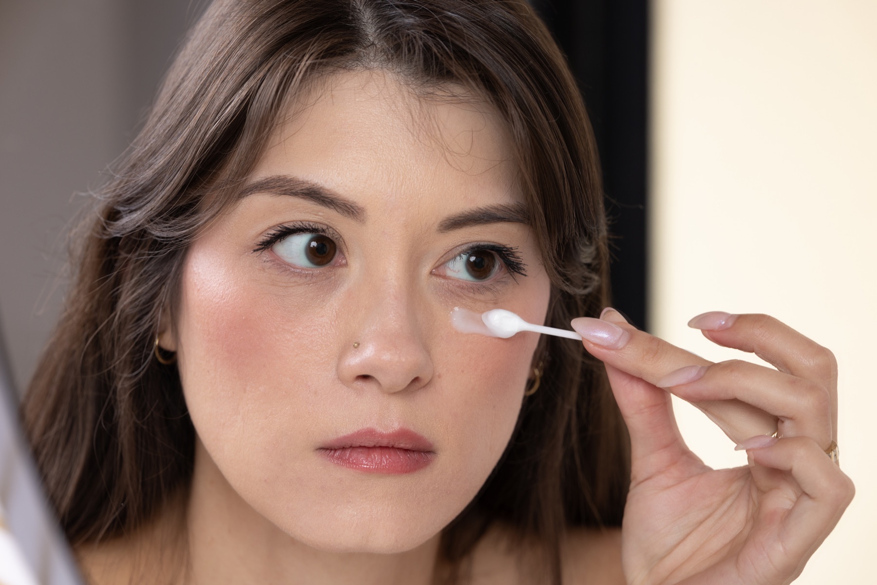 Model applying EyeGlow beneath the eye