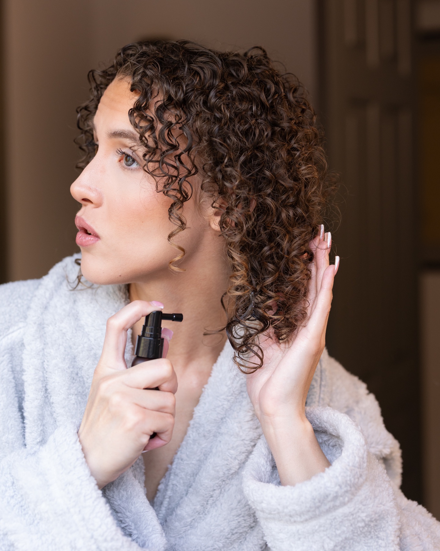 Model applying hair serum to her curls