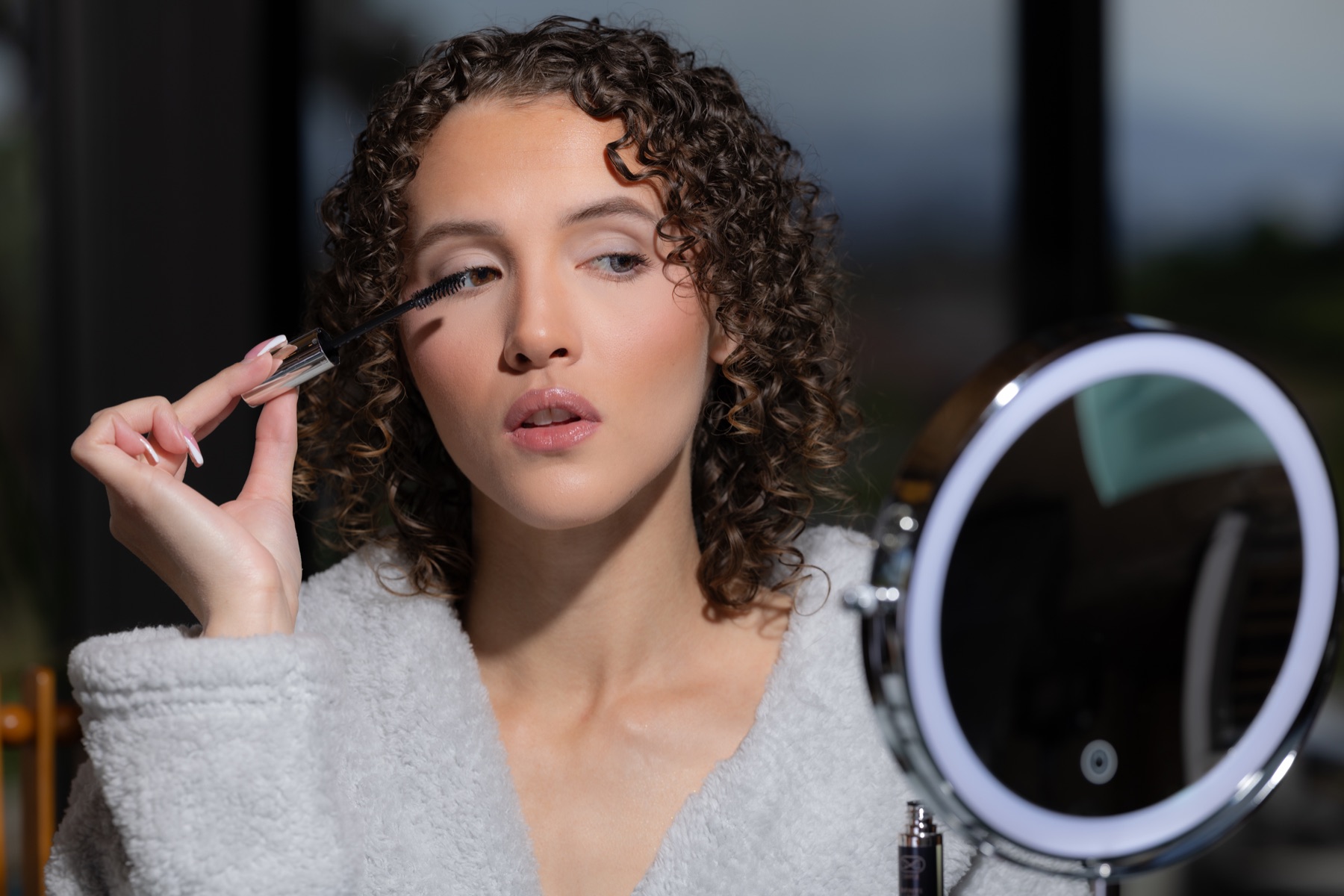 Model applying Infinite Lash at her vanity